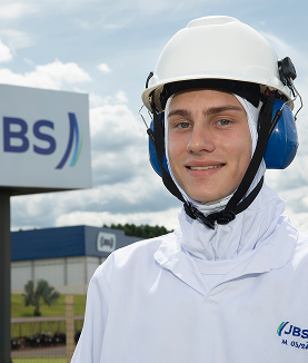 Man in white with helmet and earmuffs in front of JBS.